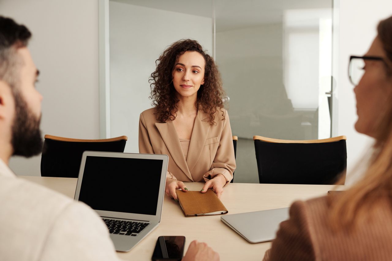 A candidate and two colleagues in a thoughtful conversation around an office table.